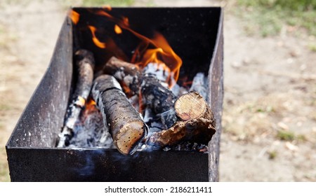 Burning Red Hot Sparks Fly From Fire. Barbecue Gril With Glowing And Flaming Hot Charcoal And Firewood