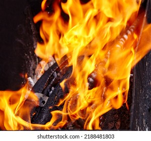 Burning Red Hot Sparks Fly From Fire. Barbecue Gril With Glowing And Flaming Hot Charcoal And Firewood