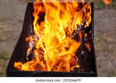 Burning Red Hot Sparks Fly From Fire. Barbecue Gril With Glowing And Flaming Hot Charcoal And Firewood