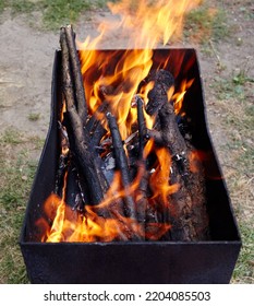 Burning Red Hot Sparks Fly From Fire. Barbecue Gril With Glowing And Flaming Hot Charcoal And Firewood