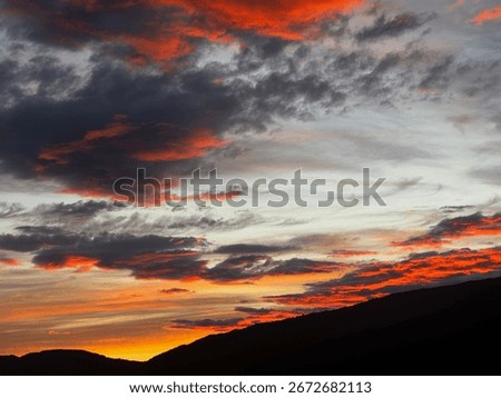Burning red sky with intense clouds glowing across the horizon, full of drama and energy.
