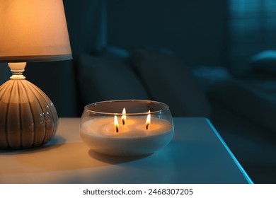 Burning scented candle and lamp on bedside table in bedroom at night - Powered by Shutterstock