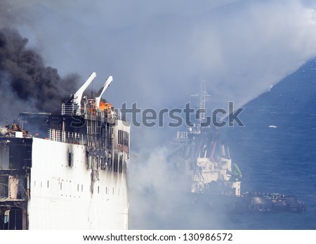 Burning ship and fire fighting boat sprays jets of water