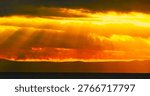 Burning sky with dramatic clouds and divine rays of light above the sea horizon