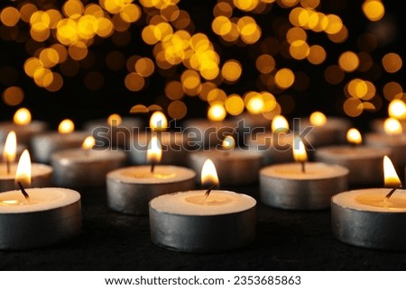 Burning small candles on black background, close up
