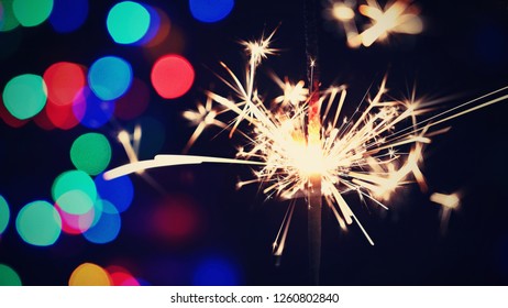 Burning sparkler with beautiful colorful background. Concept for Christmas and Happy New Year.



