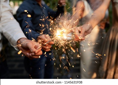 Burning Sparklers In Hands Of Party Guests