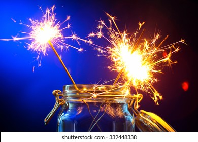 burning sparklers in a jar on wooden table on blue background - Powered by Shutterstock