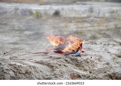 Burning sports sneakers or gym shoes on fire stand on sandy beach coast close up. Athlete burned out. Physical exertion during training concept - Powered by Shutterstock