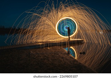 Burning steel wool spinned on the water. Showers of glowing sparks from spinning steel wool. Girl in the fire. 