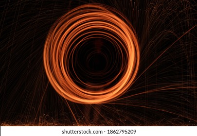 Burning Steel Wool spinning. Showers of glowing sparks from spinning steel wool. Visible noise due to low light condition. 