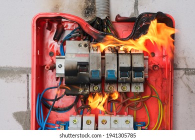 Burning Switchboard From Overload Or Short Circuit On Wall Close-up. Circuit Breakers On Fire From Overheating Due To Poor Connection Or Poor Quality Wires. Faulty Home Wiring Concept