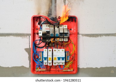 Burning Switchboard From Overload Or Short Circuit On Wall Close-up. Circuit Breakers On Fire And Smoke From Overheating Due To Poor Connection Or Poor Quality Wires. Faulty Electrical Wiring Concept