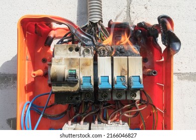Burning switchboard from overload or short circuit on wall. Circuit breakers on fire and smoke from overheating due to poor connection. Dangerous home electrical wiring concept, closeup view