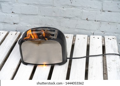 Burning toaster. Toaster with two slices of toast caught on fire over white background. Danger of careless handling of electrical appliances. Fire
