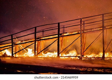 Burning wooden bridge in a raging flame close-up. Bridge on fire at dark night. Transition in Bright Hellfire. Hellfire Bridge. Bridge during intense combustion and heating. Wooden structures on fire.