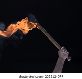 burning wooden torch in hand isolated on black background