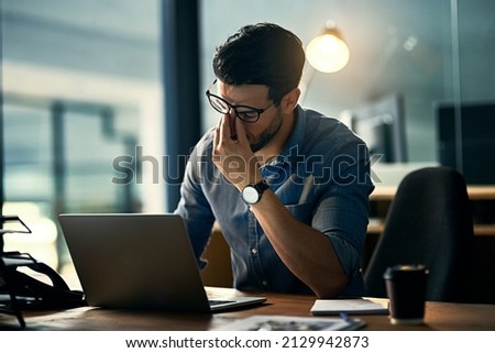 Burnout is killing his career. Shot of a young businessman experiencing stress during a late night at work.