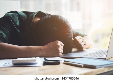 Burnout Syndrome, Man sleeping at his desk working over a laptop,Tried overworked, Freelance man working overload, Young business owner at home office,man feel tried and nap on desk. - Shutterstock ID 1434785846