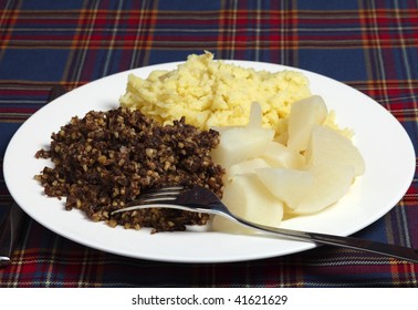 A Burns Night Supper Of Haggis, Tatties And Neeps On A Tartan Background