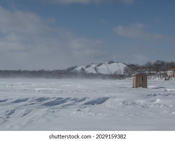 Burnsville, MN USA - February 24 2019: An Ice Fishing House In The Middle Of The Frozen Lake.  Winter May End Soon, But The Snow And The Cold Stay A Little Longer In Minnesota.