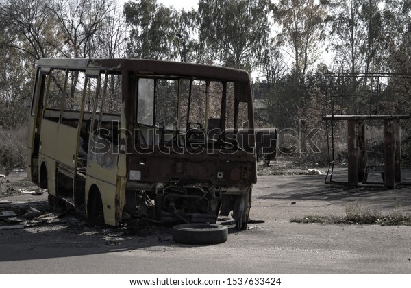 Burnt bus in an abandoned park. Card in\
the style of\
post-apocalypse.
