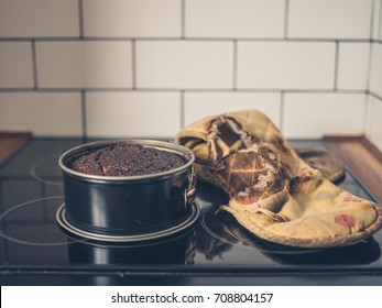 A Burnt Cake And A Burnt Oven Glove On The Cooker