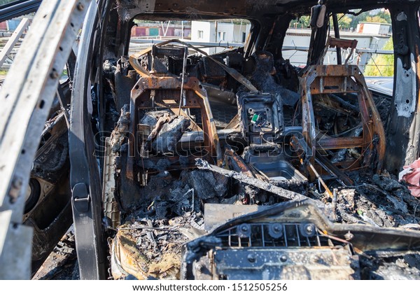 A burnt car after a fire or an accident\
in a parking lot covered with rust and black coal with scattered\
spare parts around. Robbery, arson,\
terrorism.