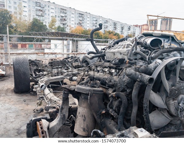 A burnt car frame after a fire\
or an accident in a parking lot covered with rust and black coal\
with scattered spare parts around. Robbery, arson,\
terrorism.