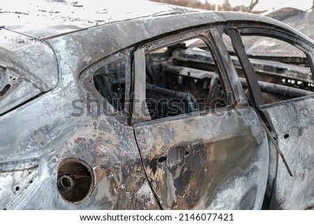 Burnt car with small flames inside of the engine. Burnt new car. malfunction that led to the death of the atomobile and people