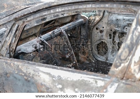 Burnt car with small flames inside of the engine. Burnt new car. malfunction that led to the death of the atomobile and people