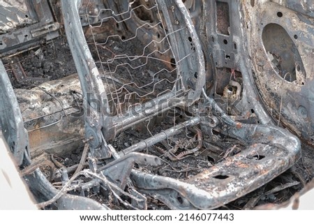 Burnt car with small flames inside of the engine. Burnt new car. malfunction that led to the death of the atomobile and people