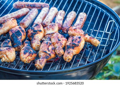 Burnt, Charred Chicken. Process Cooking Chicken Drumstick And Sausages On Barbecue Grill Outdoors. Picnic, Eating Outdoors. Metal Barbecue Grill (brazier)