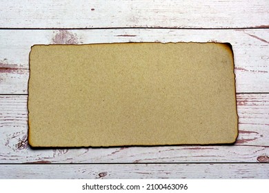 Burnt Edge Brown Paper With On Wooden Desk. Blank For Text