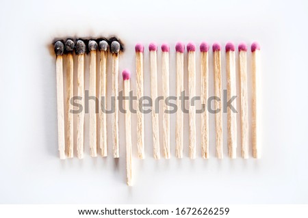 Burnt matches and whole matches on white background. The spread of fire. One whole match isolated to stop the fire. Stop destruction concept