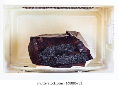 Burnt Paper Bag With Melted And Burnt Popcorn In The Greased And Dirty Microwave Oven, After The Explosion And Fire 