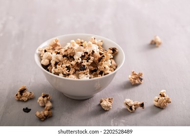 Burnt Popcorn In The Small White Bowl On Grey Ceramic