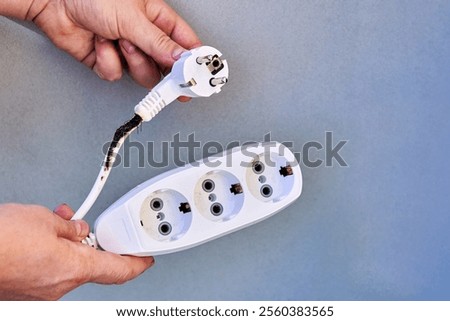 Burnt power cable with tee socket after overloading with electrical appliances.