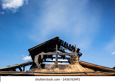 Burnt Roof Of A Wooden House Against The Blue Sky. The Concept Of Home Insurance Against Accidents, Fire In Homes, Safety Rules In Case Of Fire, Restoration Of Property After A Fire. Place For Text.