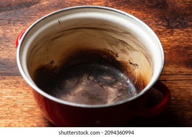 Burnt Saucepan On A Wooden Background. Spoiled Kitchen Utensils.