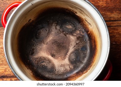 Burnt Saucepan On A Wooden Background. Spoiled Kitchen Utensils.