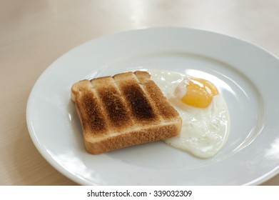 Burnt Toast And Fried Egg On A White Plate