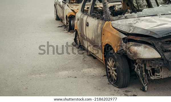 burnt-out cars are on the\
road in the yard next to houses, set on fire, accident, broken car,\
banner