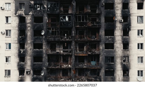 A burnt-out high-rise in the war zone. Damage to a residential building as a result of artillery shelling. War in residential areas, broken windows and burned apartments. Armed conflict in Ukraine - Shutterstock ID 2265807037
