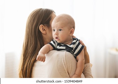 Burping Your Baby Concept. Woman holding newborn baby on hands and patting his back after breasfeeding, closeup