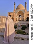 A burqa dress iranian woman taking photo of Agha Bozorg Mosque