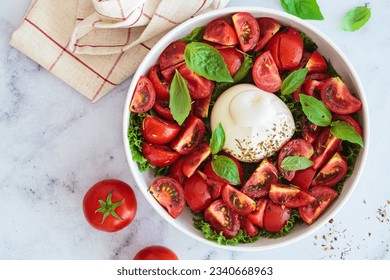 Burrata salad with tomatoes and basil in a white plate, top view. - Powered by Shutterstock