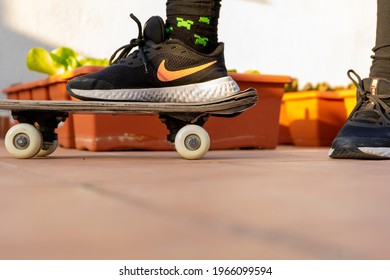 Burriana, Spain 05012021: Feet Of A Girl With Black Nike Shoes On An Old Skateboard On The Terrace Of The House