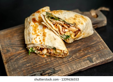 
Burrito wraps with chicken and vegetables on a cutting board, against a background of concrete, Mexican shawarma