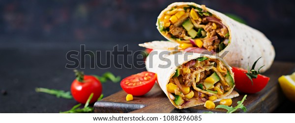 Burritos wraps with beef and\
vegetables on  black background. Beef burrito, mexican food.\
Banner